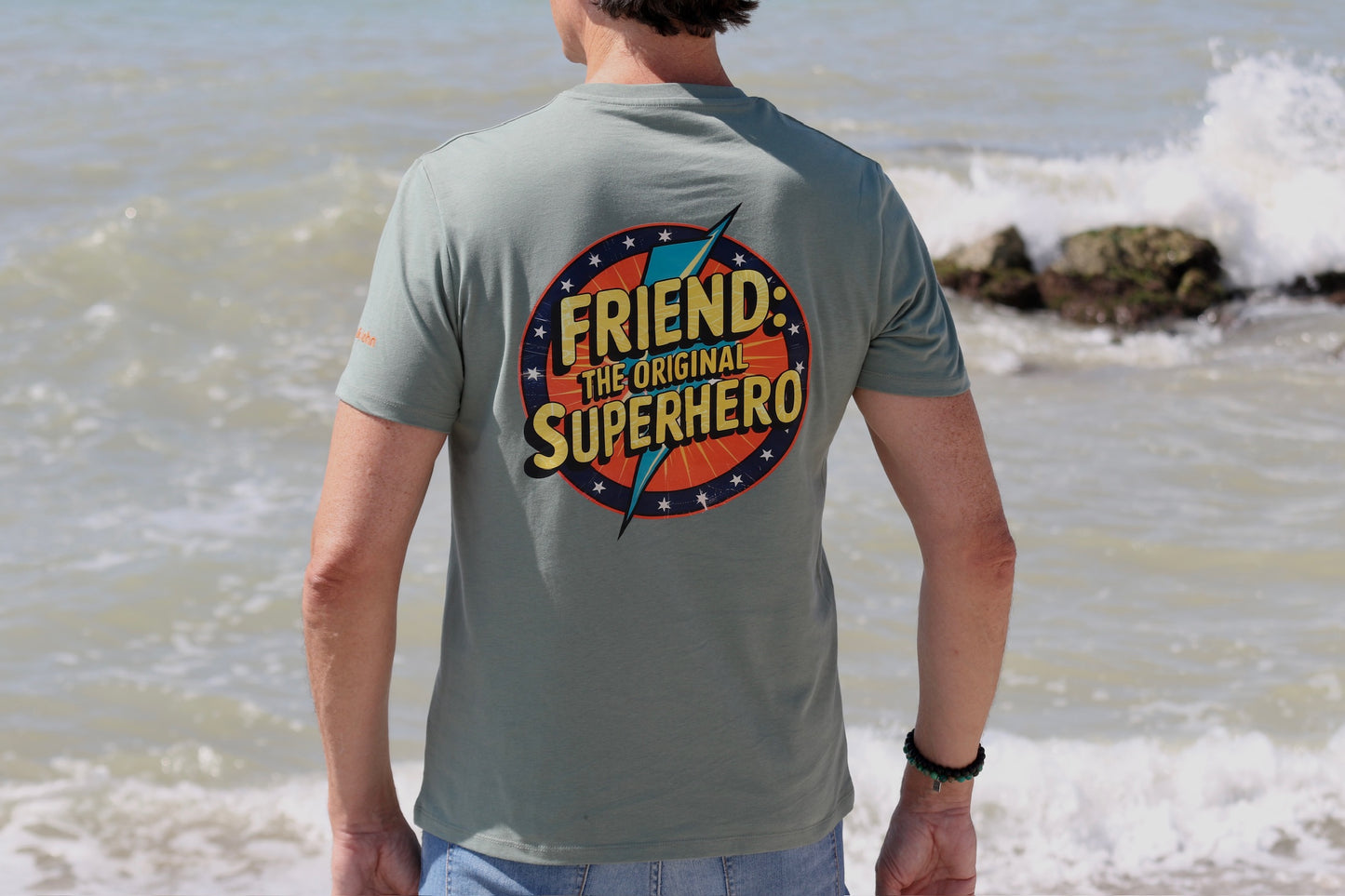 dorso de la camiseta manga corta friend: the original superhero con mar de fondo y las olas rompiendo contra las rocas