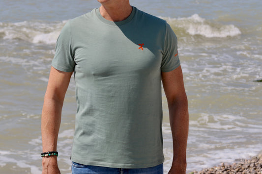 frontal de la camiseta manga corta  friend: authetical superhero en la orilla del  mar con fondo de olas rompiedo 