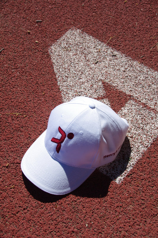 Gorra blanca Henry and John  con logo rojo magenta central sobre pista de atletismo